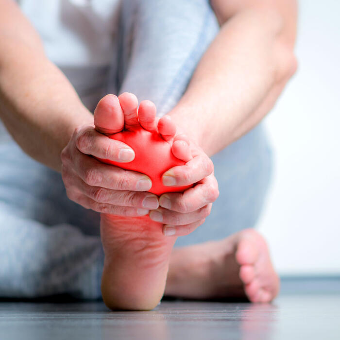 Person massaging foot with red pain highlight overlay