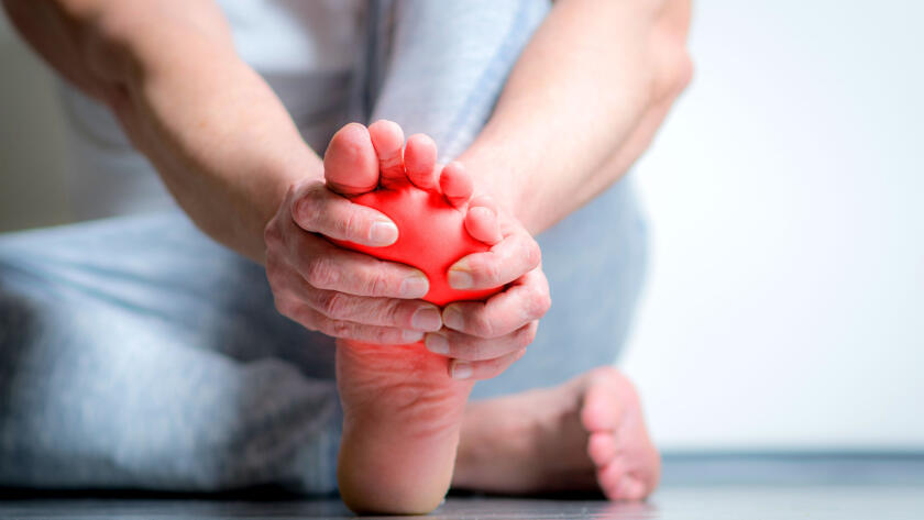 Person massaging foot with red pain highlight overlay