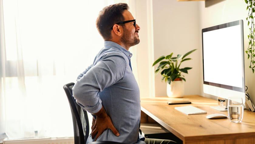 Man experiencing back pain while working at office desk
