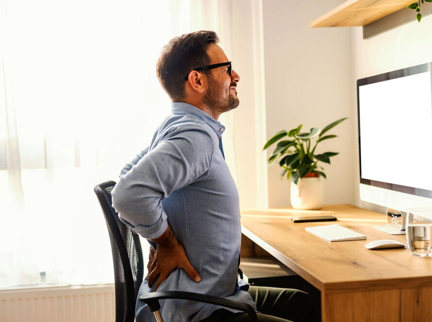 Man experiencing back pain while working at office desk