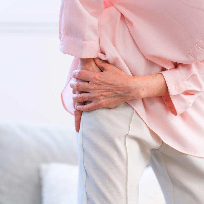 A person holding their hip, experiencing hip joint pain.