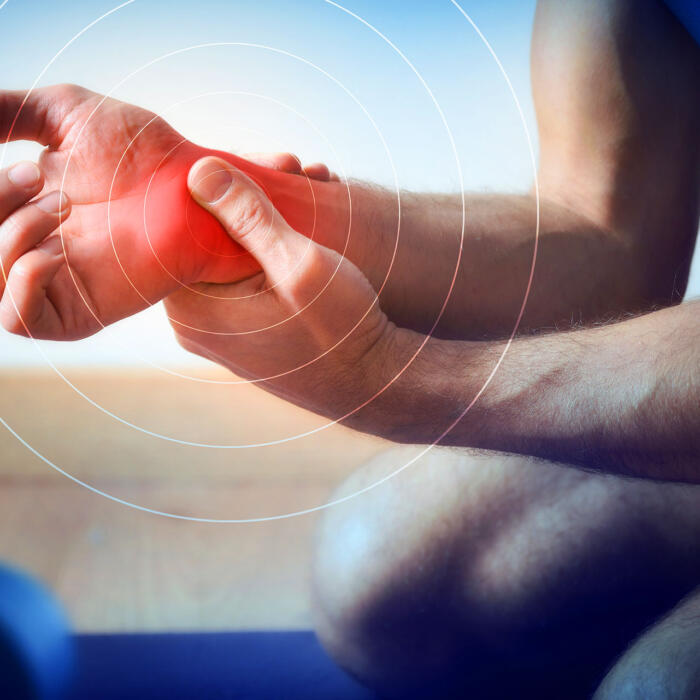A close-up view of a person holding their wrist, highlighted with a red overlay indicating wrist pain.